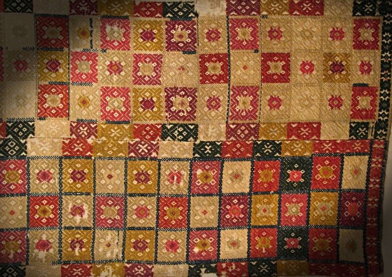 This bedcover was woven in the early 19th century – in weft-motif tabby type ‘opphämta’ on an unbleached linen warp, with coloured woollens for ornamentation and linen ground in the weft. The motifs close-up to the middle seam used to fit well on such fabrics, whilst the weaver produced two identical but reversed pieces on the relatively narrow handlooms. However, these ornamentations and colours fit poorly in this seam, indicating that it was initially woven for a long bench and later cut in half and stitched together. Such a bedcover could also be used as table decoration. |Lister district, Blekinge province. (Courtesy: Nordic Museum, Stockholm, Sweden. NM.0068443. DigitaltMuseum).
