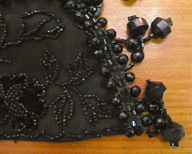 A detailed picture showing the corner of a very heavy and highly decorated black cape from the period 1870s to the 1880s made from ribbed silk and lined with a dark silk. The collection contains a rich selection of garments of this kind, but this particular example of unknown origin is not only exceptionally well preserved but has larger jet ornaments than most. (Whitby Museum, Costume Collection, 2005/21). Photo: Viveka Hansen.