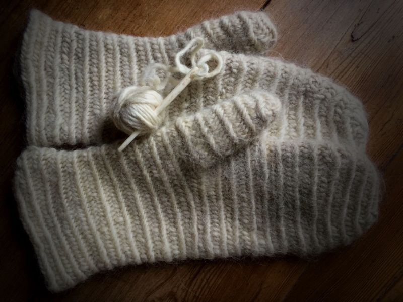 My attempt for this pair of male-sized mittens in the nålbindning technique was made with the illustrated bone needle and a thick single ply white woollen yarn. Thereafter, this pair of mittens was slightly felted in warm soapy water to create a compact, hard-wearing and warm woollen surface. The technique results in a sort of double thickness with elasticity, formed of loops. From my practical experience it is somewhat more laborious to master – than both knitting and crochet – with the various twists and turns with the needle assisted by one’s thumb, which are easy to forget if not practised regularly. To be compared with the 19th century mittens below, which has been an inspiration for my reproduction. (Private ownership. Mittens in nålbindning and photo: Viveka Hansen).