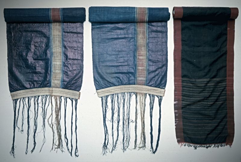 Niebuhr’s ethnographic “curiosities” which he brought back included these three striped silk (or linen) qualities from Yemen – woven in plain weave and lozenge twill borders with fringes – which would have been used for the country’s local clothing. The predominant sections of these long pieces of fabric, 365-380 cm in length, had been indigo-dyed in a number of nuances. While a forth textile was of Turkish origin with a symmetrical embroidery on white linen, 165 cm in length. These four pieces are rare survivors and most probably made in the 1760s, but judging by a museum note in 1807, Niebuhr’s collection initially included at least ‘five different Arabic garments…’. (Courtesy: National Museum of Denmark. No. EFc11-13. Quote: Dam-Mikkelsen…p. 95. [see sources]).  