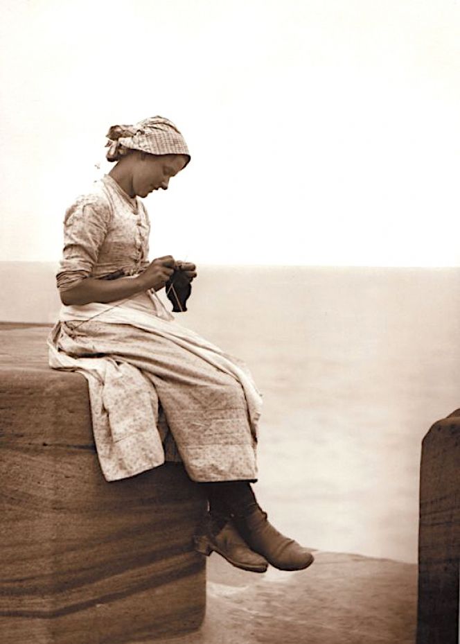 It is rare to get a glimpse of a knitting sheath in use, but this late 19th century photograph of a young woman on the West Pier in Whitby is an exception. The wooden aid seems to be fastened to the belt, visible just above her right arm. (Courtesy of: Whitby Museum, Photographic Collection. Photo: Frank Meadow Sutcliffe. B-2C). 