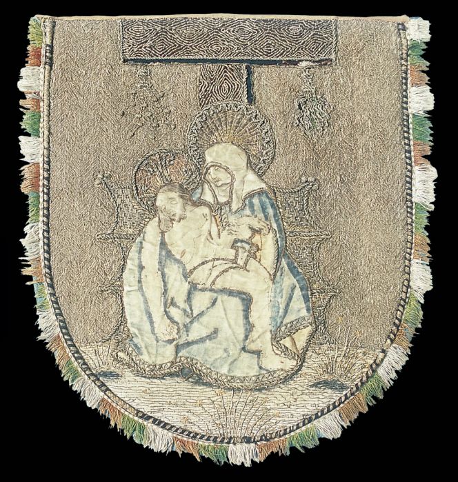 This well-preserved shield-shaped embroidery, originally decorated the back of a cope dating circa 1500. Depicted is the so-called “Pietà”, a frequently repeated motif in Christian art and particularly frequent in sculptures. This embroidery also demonstrates an advanced appliqué technique with partially blue painted white silk and metallic embroideries, on contours as well as on clothing. The background surface is fully covered with a complex laid work design of silk and metallic threads. The three-coloured silk fringe is skilfully stitched around the edge. Height 43 cm, width 36 cm. Photo: The IK Foundation, London.