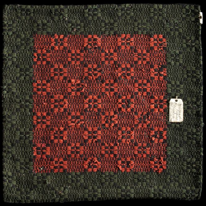 Seat cushion, woven on eight shafts, circa 1840, Bara district, Skåne province, southernmost Sweden. This “munkabälte” textile is more complex to weave than the example illustrated above. A square-shaped cushion on a linen warp – fully covered as always in this technique – has a geometrical star design across its entire surface. The centred mirror section was woven into the brocading weft due to the simultaneous use of green and red natural-dyed wool picks. In contrast to the upper and lower edges, where the brocaded weft could be shuttled with green wool only, which made this part of the weaving process quicker. It may be noted that the shuttled main weft alternates during the weaving with the picks (either shuttled or inserted by hand) and is distinctly visible in all the small black staples and cubes. The contemporary back fabric is also preserved as a handwoven twill, with a linen warp and a woollen weft. Even if both of these introduced textiles are similar in size today, the main difference is that this one was originally woven as a seat cushion with a suitable back fabric, whilst a small section from a bedcover above was remade into a pad or simply saved as a memory of a once-colourful furnishing textile. (Courtesy: The Nordic Museum, Stockholm. NM.0324905. DigitaltMuseum).