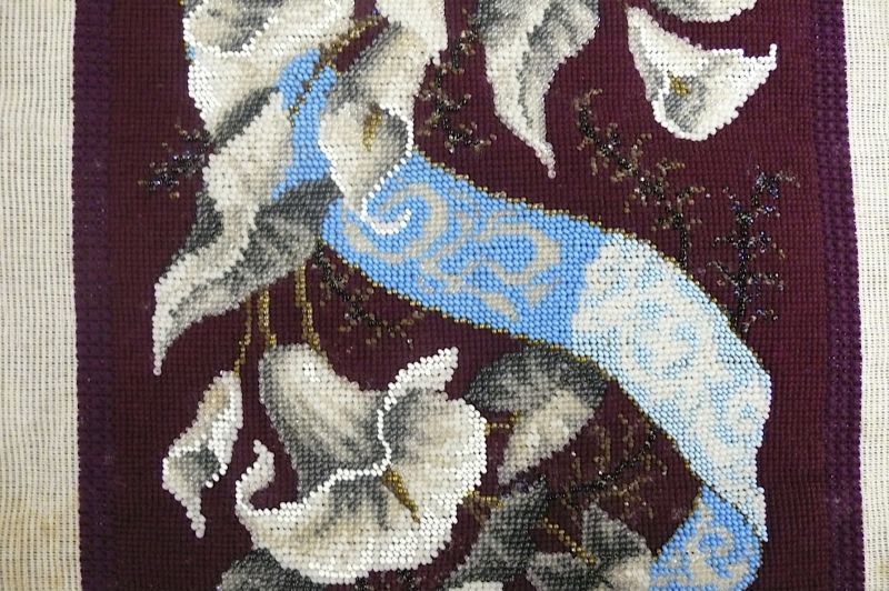 Another example shows part of an extraordinarily complicated bead embroidery against a wine-red Berlin wool embroidery background. Completed circa the 1860s-1880s, but never mounted or used despite the considerable work that must have gone into it. Beads in matching colours were particularly popular additions to these types of embroideries. (Collection: Whitby Museum, Costume Collection, COS3). Photo: Viveka Hansen, The IK Foundation.