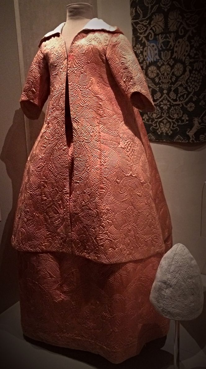 A somewhat later (1770s-80s) corded silk quilting is part of a two-piece hooded jacket and skirt, which demonstrates one popular way for a well-to-do lady to keep warm indoors. This type of garments were multi-layered with wadding inserted between the outer fabric and lining, stitched together with backstitch etc in artful motifs. The warming middle-layer could for instance be of silk, cotton, carded wool or linen tow. To my knowledge however, 18th century garments linked the Piper family or other individuals connected to Christinehof manor house have not been preserved. (Collection: Designmuseum Danmark, Exhibition ‘Fashion & Fabric’ 14a-b/1982). Photo: Viveka Hansen in June 2018.