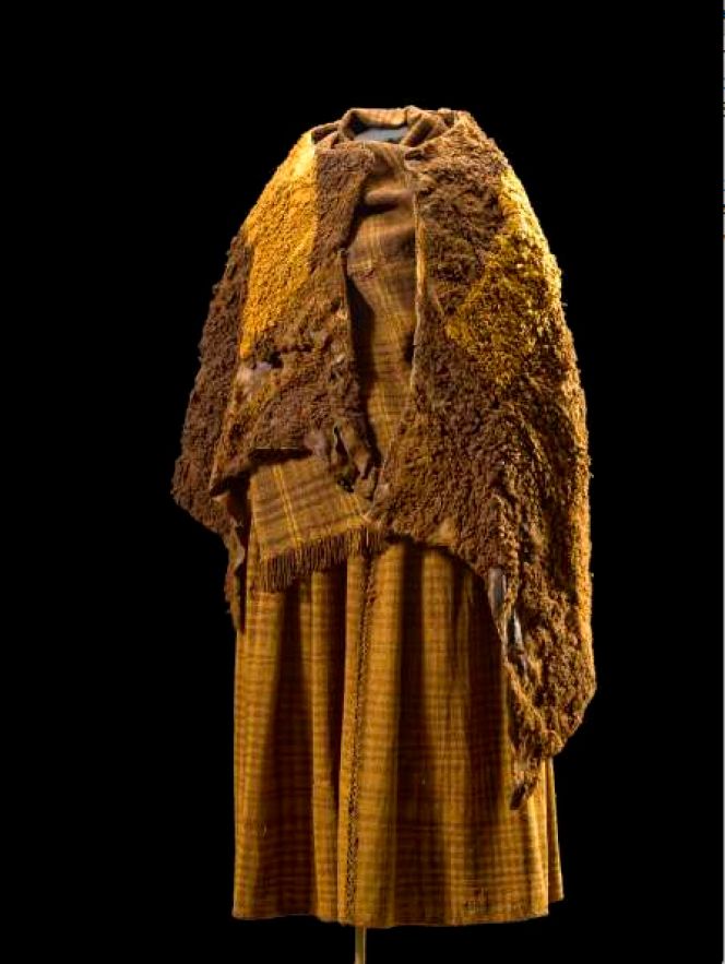 This very well-preserved Danish Iron Age bog find from “Huldremose”, originating  from the 2nd century BC can give good insight and be a comparison into a woman’s  clothing from a wider geographical Nordic area. The more than 40 year old female was  once buried fully clothed along with all her garments – consisting of a checked woollen  skirt and scarf together with two skin capes – have been studied in great detail by the  National Museum. Her clothing of wool was also dyed, explained by the museum in  the following way: ‘The long period in the water of the bog has turned the clothes  brown. Colour analysis has shown that originally the skirt was blue and the scarf  was a red colour’. (Courtesy of Nationalmuseet in København, Denmark.)