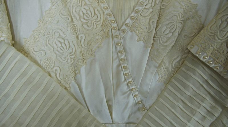 The second dress from this period is of cream-coloured silk and in a high-neck Edwardian style, decorated with broad machine-worked chemical laces, narrow prepared pleats/tucks and a large number of pearls on both sleeves and neckband. (Collection: Whitby Museum…, Costume Collection, 2006. 42.8). Photo: Viveka Hansen, The IK Foundation.