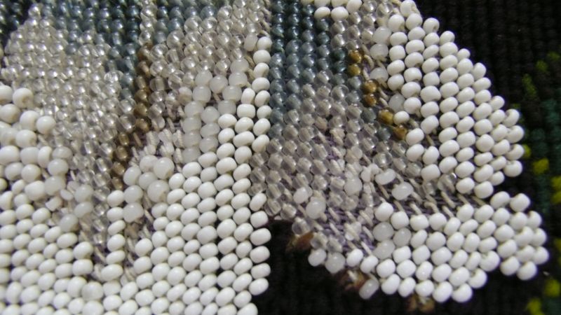 In this closeup, it is visible how the beads had been threaded on a cotton thread one by one, each bead was carefully stitched onto the canvas ground before the next bead was put on the thread and so on. (Collection: Whitby Museum, Costume Collection, COS5). Photo: Viveka Hansen, The IK Foundation.