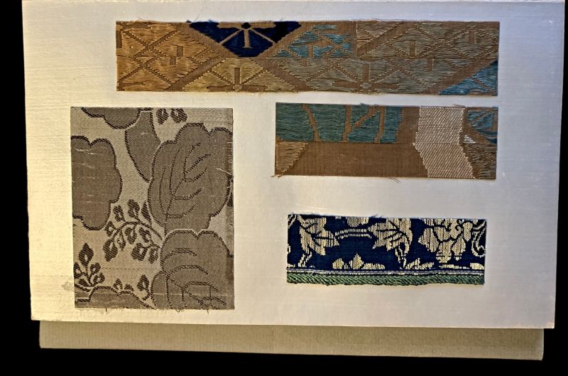 When the selvedge is visible in these sample catalogues, it shows a slight unevenness, indicating hand-weaving. For example, the blue fabric in the left-hand corner reveals that this complex figure twill quality with a double warp system was woven on a handloom. The two fabrics above illustrate a different technique with very long floating weft threads, which creates a shiny silk appearance but also results in a very delicate quality, almost unsuitable for clothing given their extraordinary complexity. (Collection: Design Museum Denmark, København. (The Library. Sample Book: I19072 Ø004). Photo: Viveka Hansen, The IK Foundation.