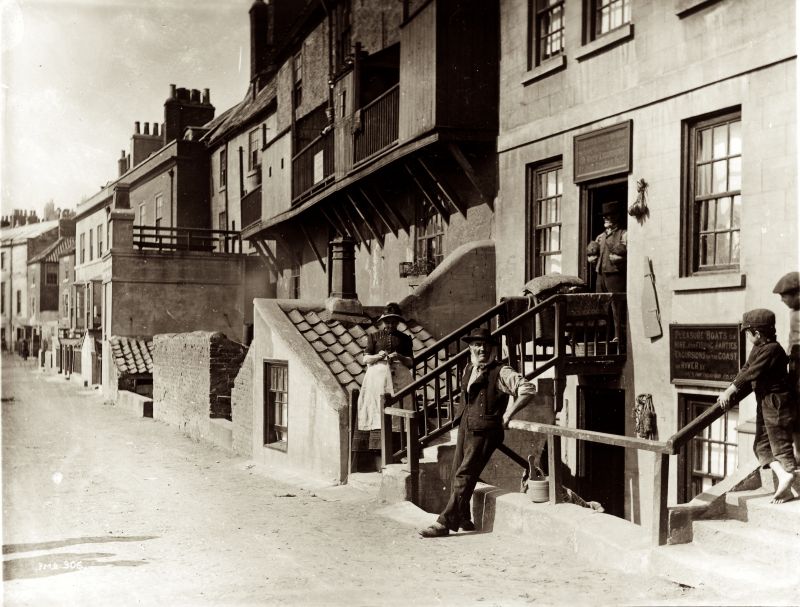 A woman knitting on Pier Road, Whitby. Knitting was an ideal occupation for filling spare moments, both indoors and out of doors. To knit stockings or other small garments were especially practical while standing or walking, but also in this picture the sheath (if in use) was not visible for the camera (Courtesy of: Whitby Museum Library & Archive, Photograph book two, 2/35. Unknown photographer).