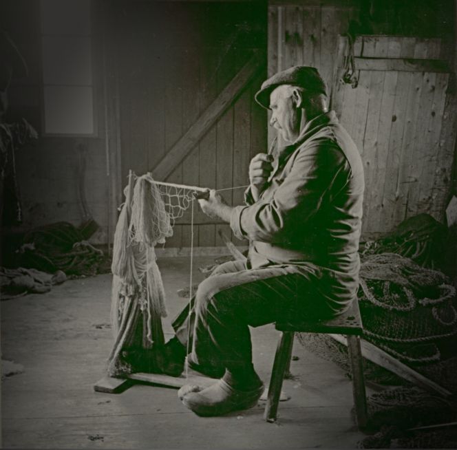 Tying nets with a special wooden needle onto which the coarse yarn could be wound during the work in progress was essential knowledge of fishing families, a craft which had had a long tradition in the coastal regions in the Nordic area. Such a method was used prior to Carl Linnaeus’ and his apostles’ written observations from the 1730s to 1770s, equally as this handcrafted tradition still was in practice during the 1930s – as demonstrated in this photograph. | The fisherman Johan Sjögren tying a fishing net in 1936, Gunnarstorp, Småland province in Sweden. (Courtesy: Kalmar Läns Museum. KLMF.Söderåkra00118. Digitalt Museum). 