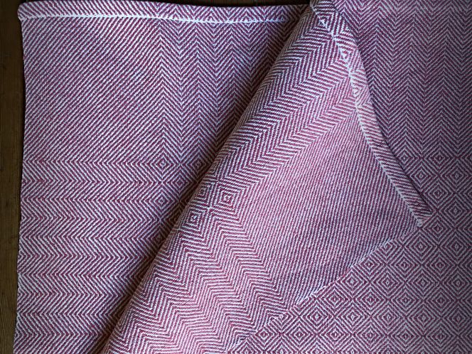 My historical reproductions of the “gåsögon” technique are introduced by this hand-woven tablecloth, measuring 110 cm x 110 cm, made of cottolin yarn (machine-spun with a mix of cotton and flax fibres), with a white warp and red weft. The aim of adding a long-lasting textile to one’s home was the same as it was 150-200 years ago; however, two aspects of the weaving technique, in particular, differ from the 19th-century weavers’ options. Firstly, the cottolin yarn was unavailable, so a cotton warp and linen weft were probably preferred or linen yarn for both warp and weft. Handlooms used in domestic settings also traditionally had a limited width, so a tablecloth of this size was woven in half-width. After the weaving, two identical pieces of fabric were stitched together with the finest stitches. (Private ownership). Photo and woven tablecloth: Viveka Hansen, The IK Foundation.