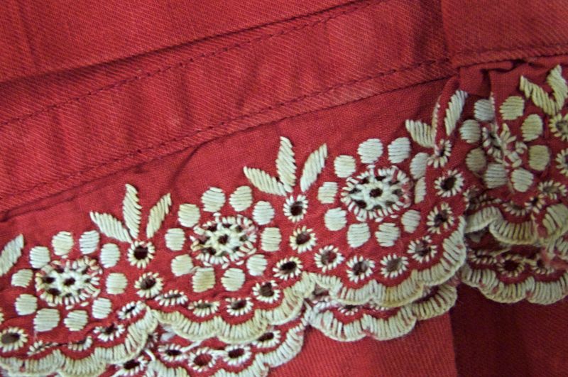 Detail of embroidery on an Edwardian bathing costume. This second loose-fitted garment is of somewhat later date – about 1900 to 1910 – machine-sewn in red cotton with short sleeves and bloomers reaching down to the calf, a typical style of the period for women, fastened with white cloth buttons in front and wearable with the addition of a matching belt around the waist. The garment has been marked ‘R. Longland’ on a sewn-in cotton label and has a machine-embroidered decorative border in contrasting white. (Collection: Whitby Museum, Costume Collection, GBD 108). Photo: Viveka Hansen, The IK Foundation.