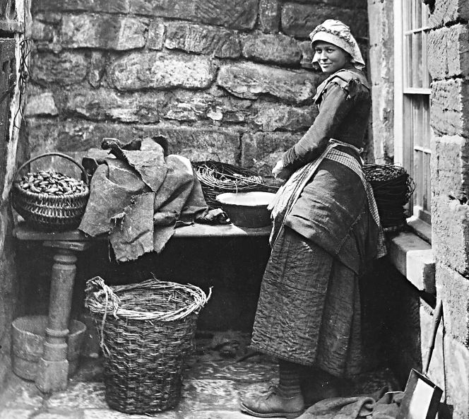 A third photograph,’ Girl bating lines’ taken by Frank Meadow Sutcliffe in the coastal village of Runswick Bay (north of Whitby) circa 1880, also gives a detailed view of a young woman’s traditional bonnet. The other garments of her working dress consisted of a quilted petticoat worn underneath her woollen dress, which was necessary for warmth and durability during hard outdoor work in the fishing communities along the Yorkshire coast. Some women’s work included baiting lines, cleaning mussels or collecting bate along the beaches. (Courtesy: Whitby Museum, Photographic Collection, Sutcliffe. 4-8, part of the photo).