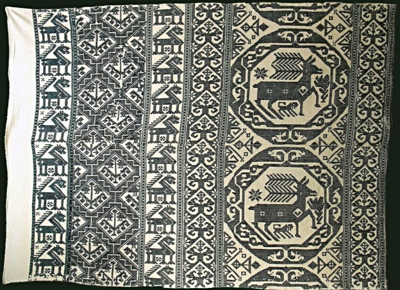 This well-preserved textile (133cm x 187cm) was woven in the Ingelstad district in the southeastern corner of Skåne province. Due to the similarities over time for these ‘dukagång’ wall/ceiling coverings, woven with unbleached or bleached linen (warp and ground weft) and blue woollen ornamentation (weft), it may not be more precisely dated than a hundred-year period from 1750 to 1850. Such comparable wall coverings were repeatedly listed in many estate inventories. For instance, this one, dated 21 June 1760, after the farmer tenant Christer Richardsson in Hagestad village, Ingelstads district. This home owned a substantial number of linen and woollen interior textiles. Among these were listed: ‘1 wall cover, 5 Daler in copper coins’ and one of the same noted as ‘old’, valued at ‘1.28’ only. These two wall decorations were most probably woven in the traditional “dukagång” technique in white and blue on various borders, similar in style to this illustrated example. (Courtesy. The Nordic Museum, Stockholm, Sweden. No: NM.0207058. DigitaltMuseum).