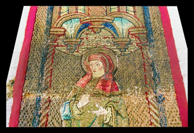 A close-up detail of the patron saint Brigit of Kildare of Ireland, demonstrates the amount of gold metallic thread used in this laid work, while various shades of fine silk gives life to faces, clothing, architectural details as well as fastening the gold embroidery with fine stitching. Photo: The IK Foundation, London. 