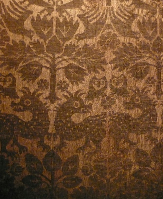A close-up image of a fully preserved late Medieval chasuble once used in nearby Lund Cathedral is a representative vestment showing the complex silk fragments imported from the Continent to the Nordic area. This red half silk with membrane gold – consisting of a gold strip wound around a core of silk – has darkened in shade. However this vestment is not regarded as Italian by the Cathedral Museum, but instead of possible German origin. (Photo: Viveka Hansen, exhibition at the Cathedral Museum, Lund University Historical Museum).