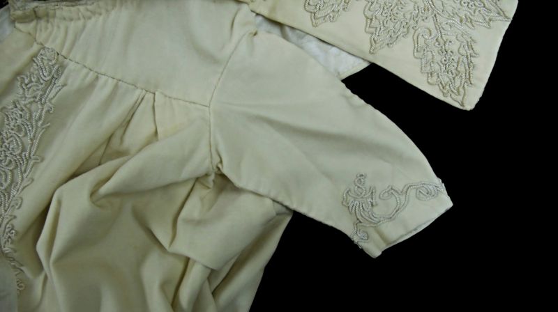 The second garment for a baby features similar decoration, this time crafted with cotton perle yarn into a leaf-like design that, based on its material and stitching details, likely dates from around 1900. This christening cloak, made of fine cream-coloured wool, is a wide, richly decorated cape; while the small matching baby jacket sewn inside would have provided extra warmth and helped the baby look particularly elegant both before and after the baptism. (Collection: Whitby Museum…, Costume Collection, 2005/48.5). Photo: Viveka Hansen, The IK Foundation. 