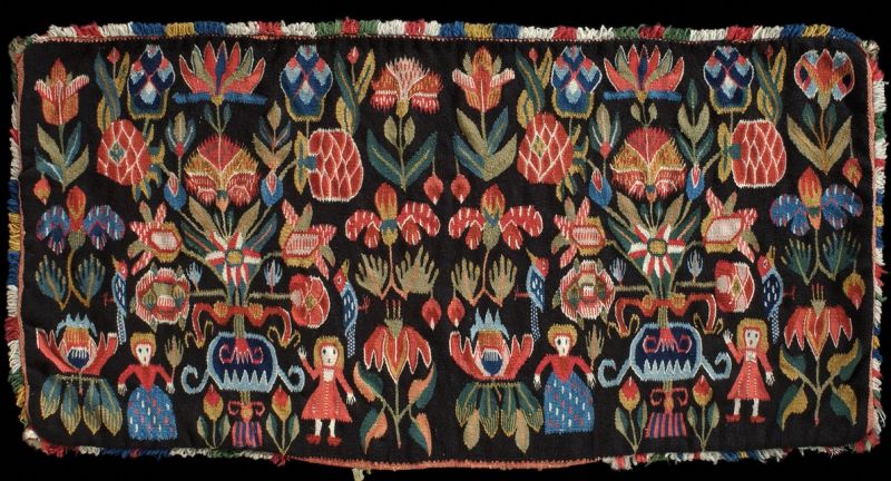 This well-preserved cushion woven in a farming community in Torna district in the province of Skåne (Sweden) around year 1800 is typical in its flower design, and contrasting colours carefully woven into the dark brown background. Such dove-tail tapestry with a linen warp and woollen weft, like this example, was in use only for special occasions in the form of carriage cushions when travelling to church or indoors during Christmas, weddings or other festive family moments. The cushion was originally filled with down and feathers for comfortable seating, probably removed in 1873 when the textile was acquired by the Nordic Museum. However, the decorative and protective corner tassels of silk and broadcloth pieces are still extant as well as a woollen fringe and the red plain woven woollen cloth for the back. (Courtesy: Nordic Museum, Stockholm, NM.0001233).