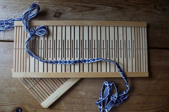 As a comparison; two modern Swedish rigid heddle looms made after older models. The wider loom have been used for ribbons, like the illustrated heart-shaped one of blue wool and linen. While the narrower variation of loom can be used for plain as well as ornamented designs. Photo & woven ribbon: Viveka Hansen.