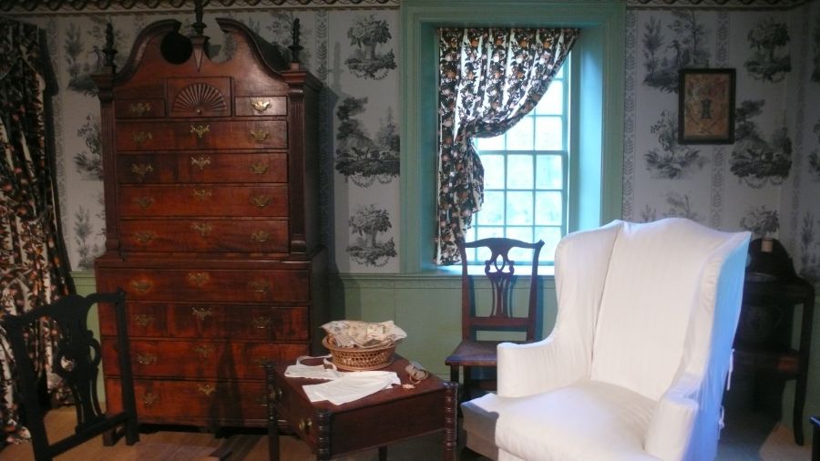 The Nineteenth-Century Chamber (1800-1820) at Concord Museum is one of several period interiors, built upon research from a variety of archival and visual sources giving the visitors an idea of the local domestic life during the 18th and 19th centuries. All exhibited fabrics are reproductions developed from studies of the town’s estate inventories, imported qualities via English sample books, upholsterer’s account books, bills of sale, original textile furnishings or fragments. This depiction of an early 19th century chamber clearly demonstrates the increasing use of printed cottons and woven upholstery fabrics. In stark contrast to the museum’s 1750s parlour interior, presenting a time when woollen cloths and checked linen qualities were primarily in use. Photo: The IK Foundation, London.